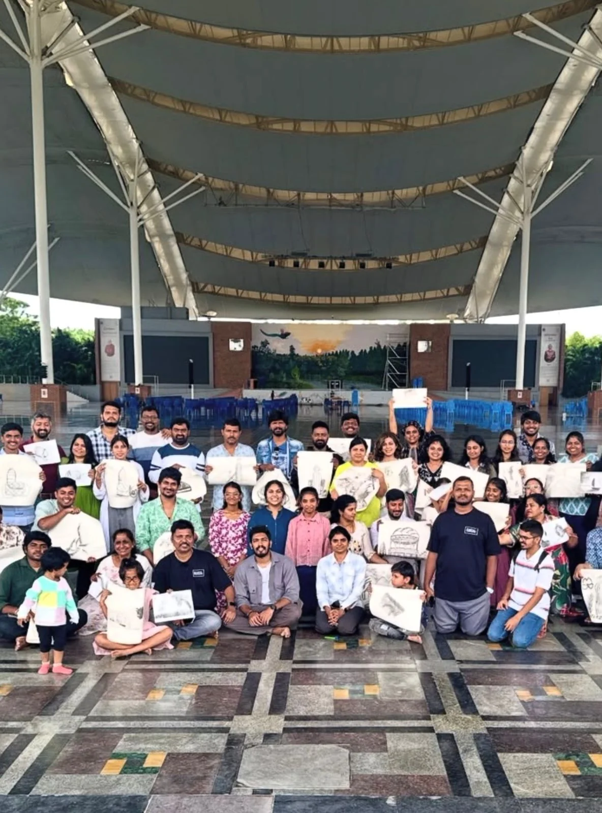 Creativee Community participants holding charcoal drawings at Kanha Shanti Vanam