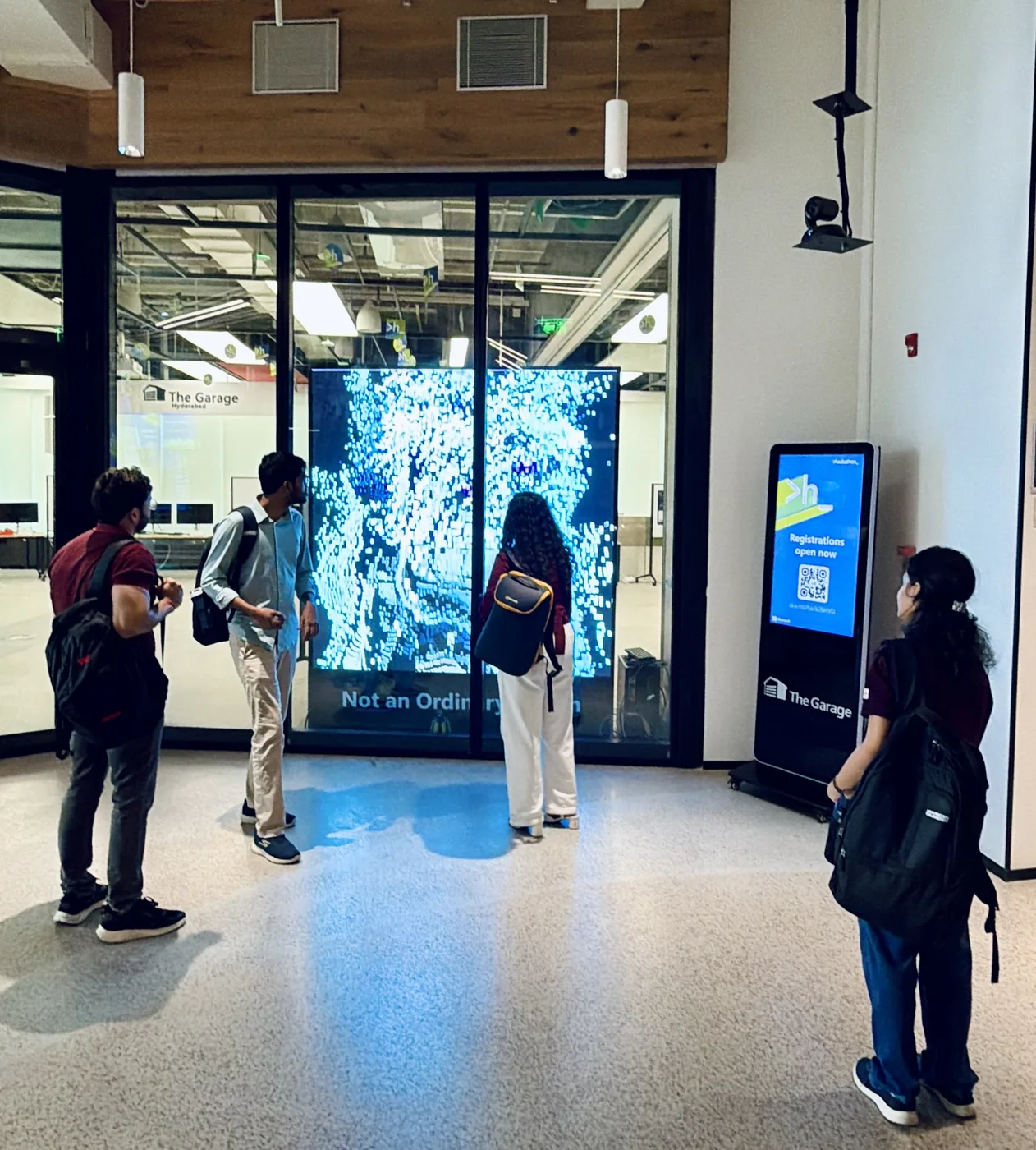 Visitors watching a large interactive 3D particle installation at Microsoft Garage Hyderabad during Hackathon 2026