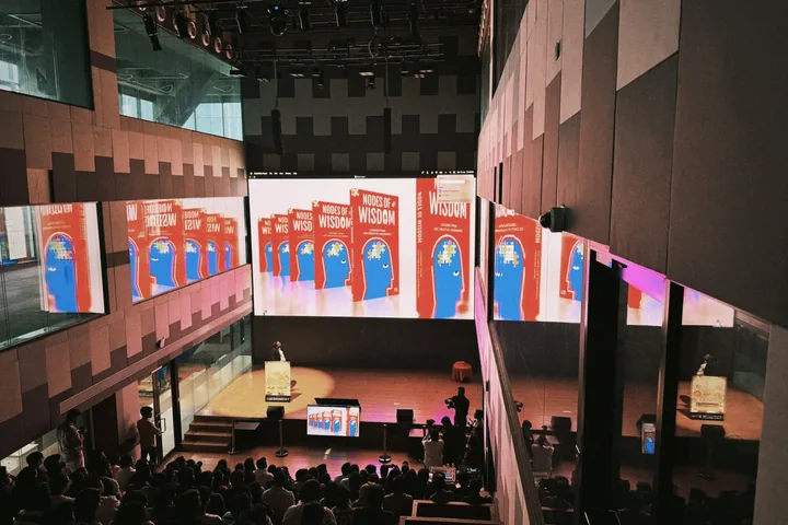 Nodes of Wisdom displayed across a launch stage