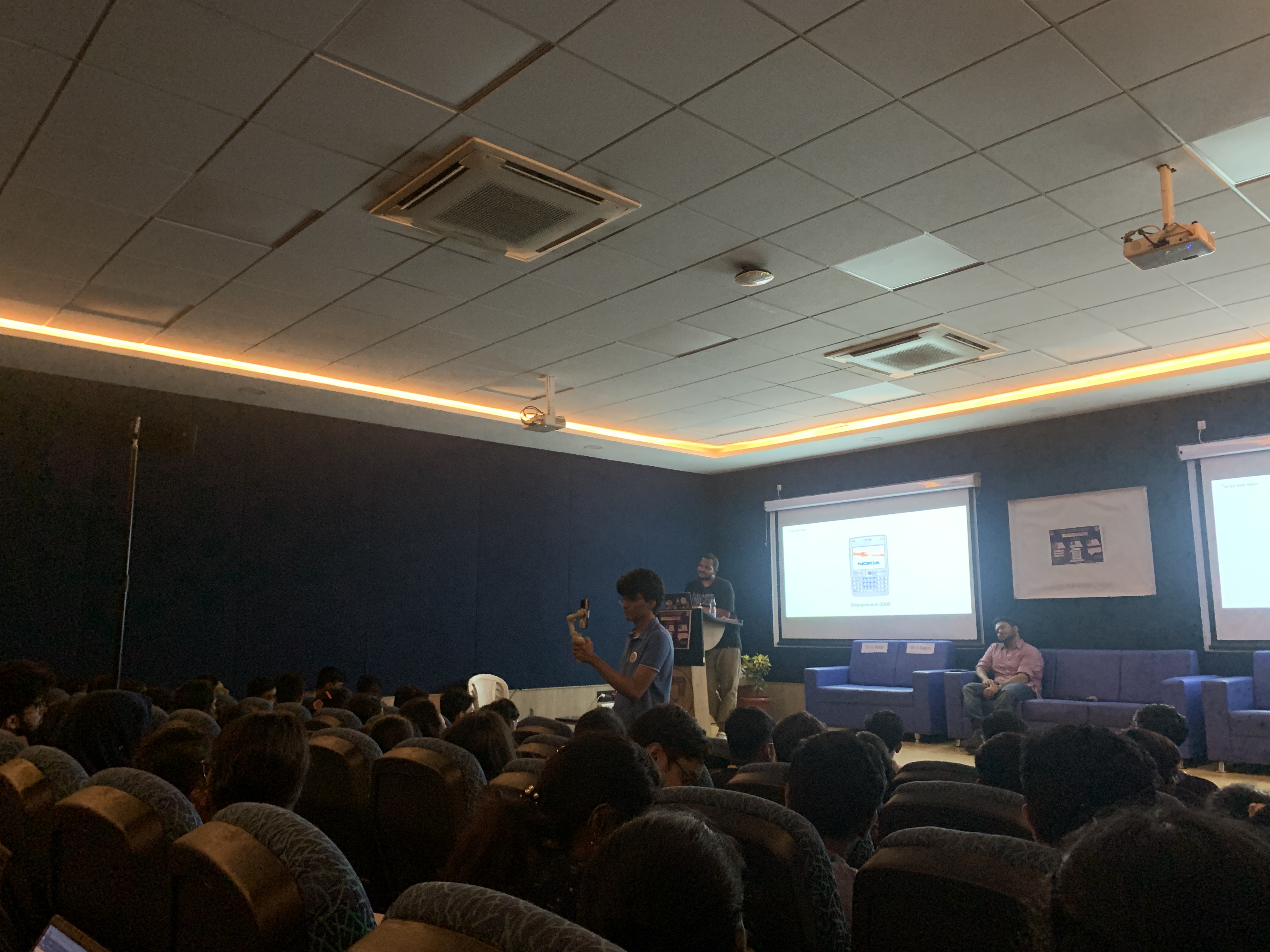 Tejj talk in a packed auditorium with product UI on stage screen